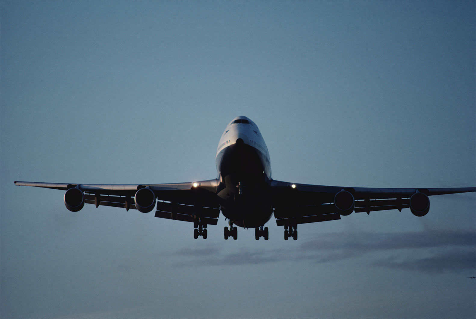 plane flying with landing gear down and lights on